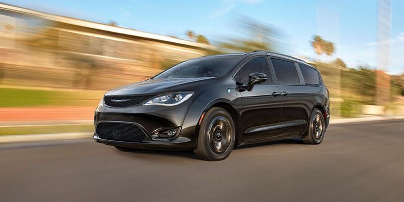 Black Chrysler Pacifica minivan driving on a road, with motion blur in the background.